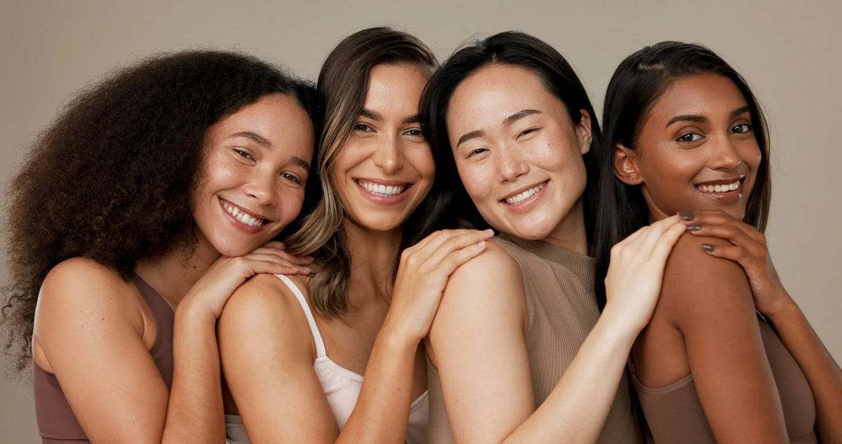 4 women with different skin tones touching each other shoulders
