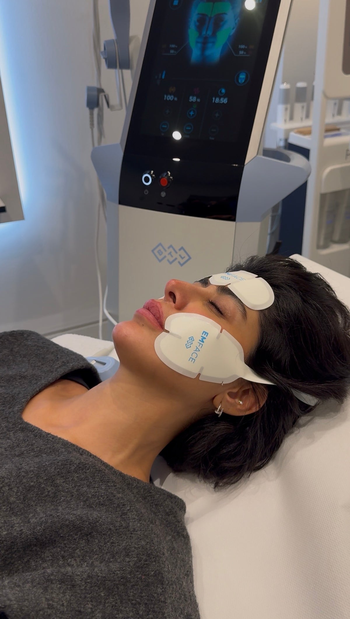 Woman having a treatment with electrode pads applied to her face, using a facial skincare device