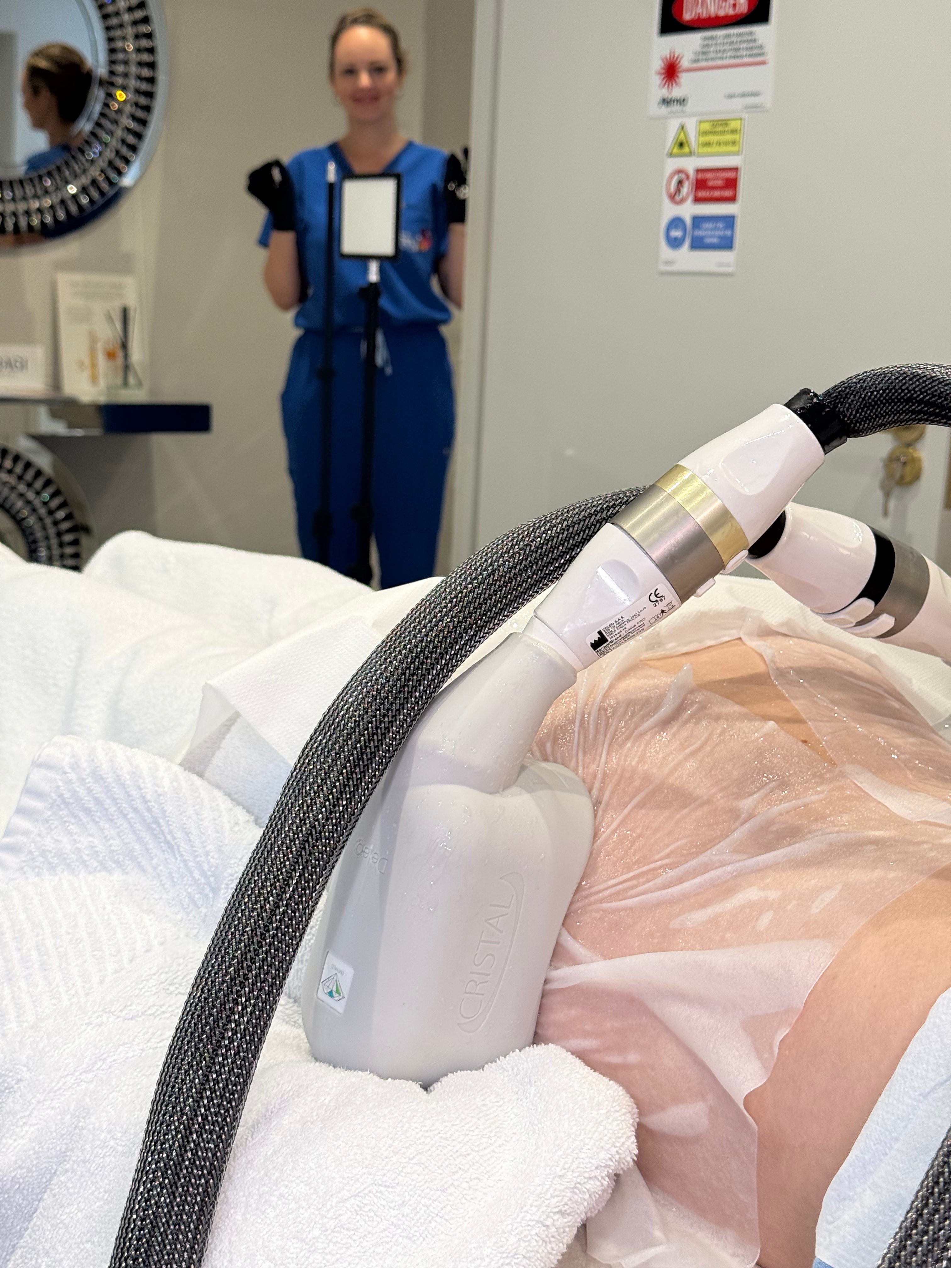 A close-up of a white and silver cosmetic laser device being used on a patient