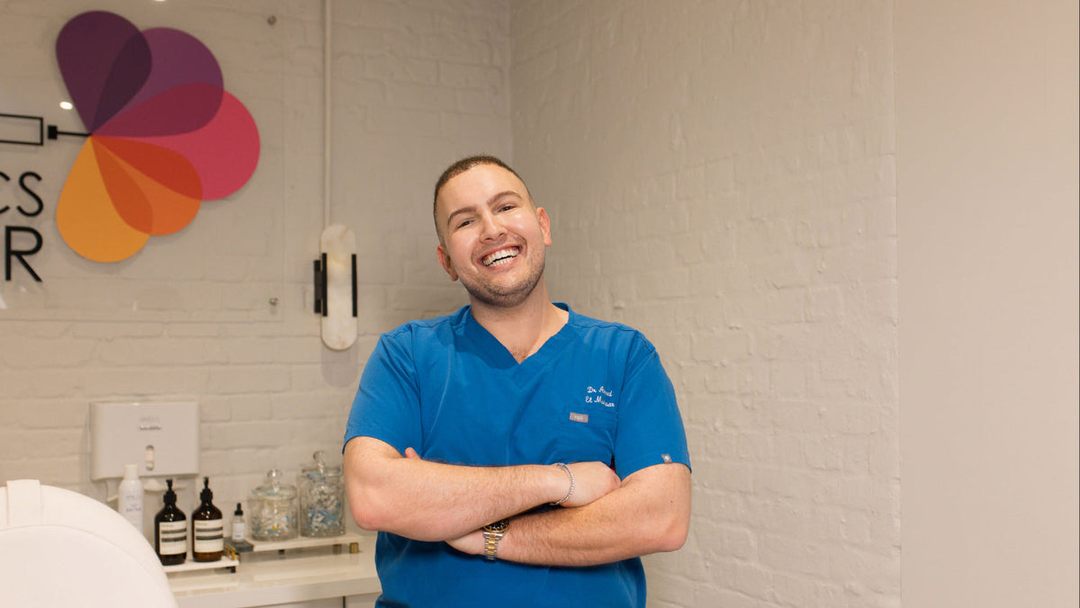 Dr Ahmed smiling Infront of the company logo